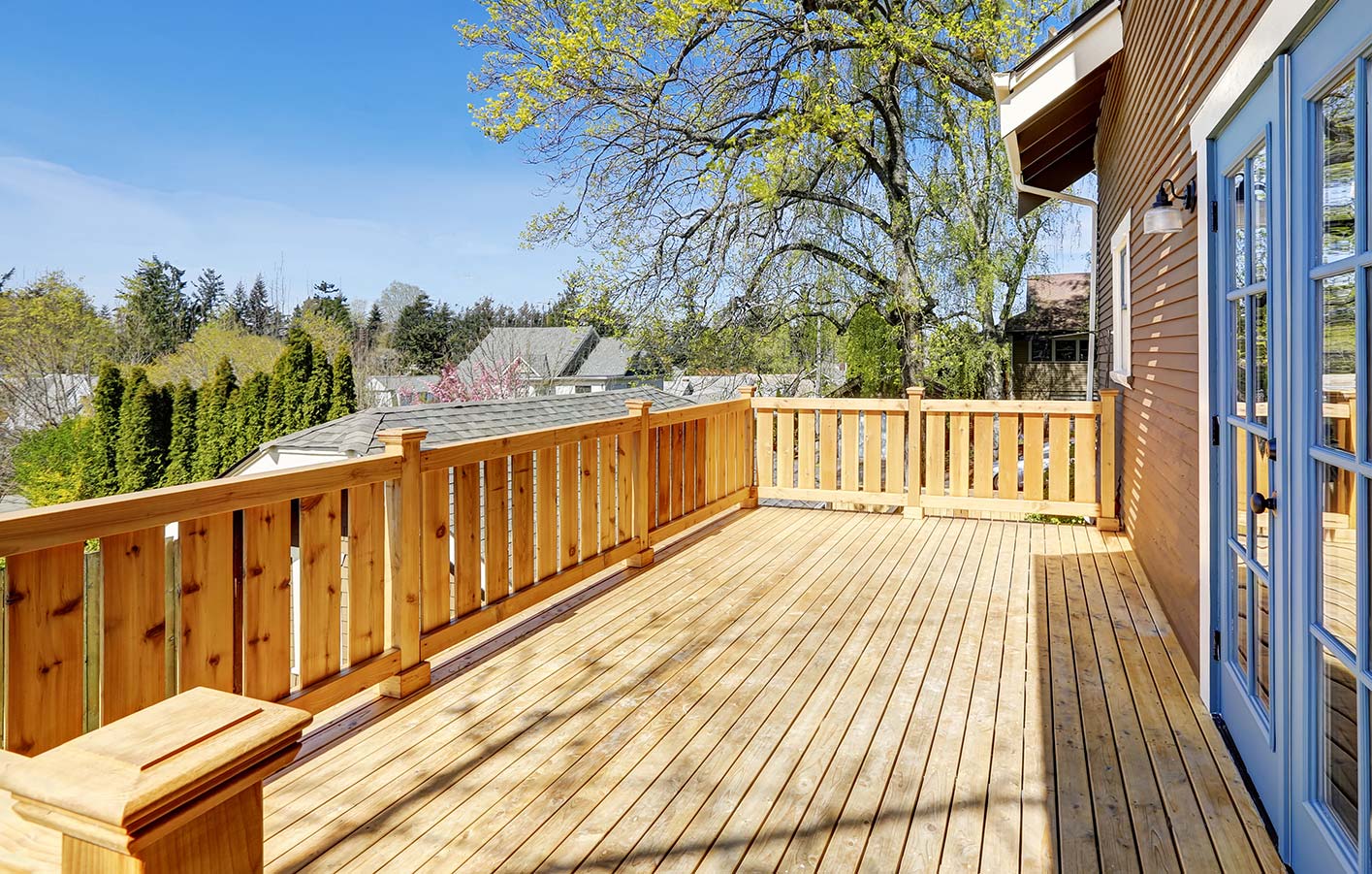 Terrase aus hellen Massivholzdielen und eine blaue Terrassentür