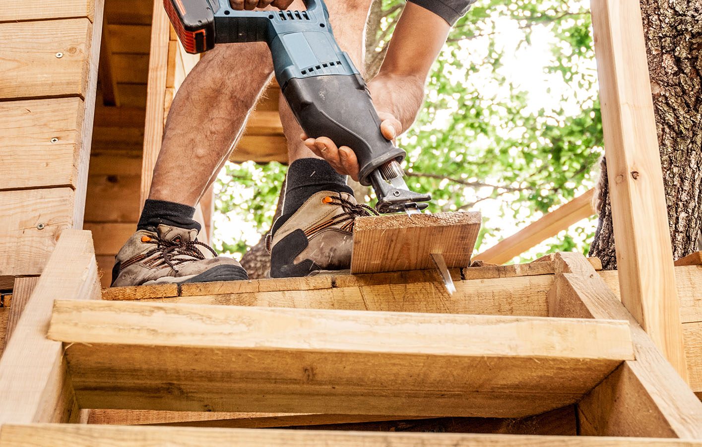 Person baut ein Holzbaumhaus